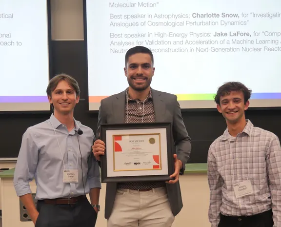 Jake LaFore holds his Best Speaker certificate between UPCC co-directors Zachary Larter and Jeremy Goodkin, in front of the award slide